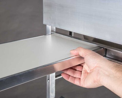 Eine Hand zieht eine verschiebbare Ebene aus dem Kommissionierwagen