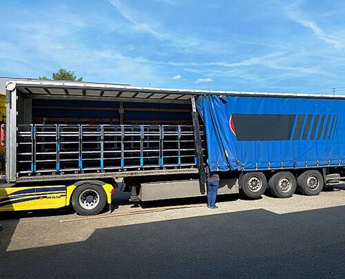 Ein Lastwagen ist mit vielen Kommissionierwagen beladen und ist bereit zur Abfahrt. Das Seitenverdeck wird geschlossen.