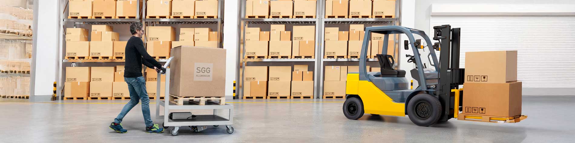 Kommissionierer in einer Lagerlogistik, der eine Kiste auf einem Plattformwagen transportiert