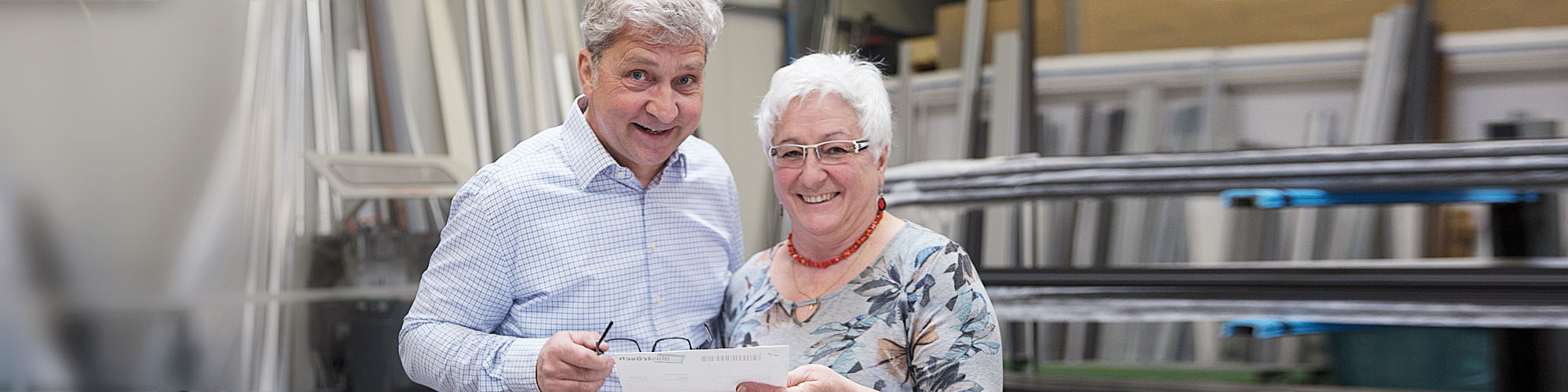 Steffen Grieß, Geschäftsführer von SGG Aluminium in Bad Waldsee, lächelt freundlich in der Produktionshalle zusammen mit einer Mitarbeiterin 