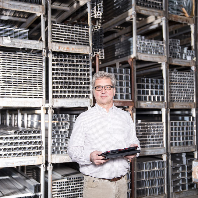 SGG Aluminium Geschäftsführer Steffen Grieß steht vor dem Warenregallager mit Aluminiumprofilen